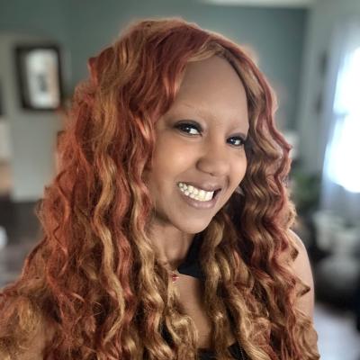 headshot of a bi-racial woman with reddish hair who is smiling