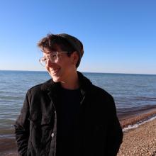 Person smiling in front of a beach